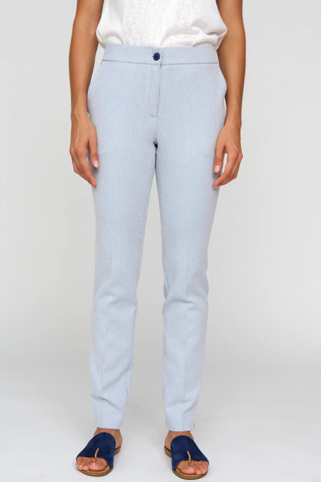 Model wearing 'Cesta24' light blue pinstripe trousers with a straight-leg fit and button closure, paired with a white top and navy blue sandals.