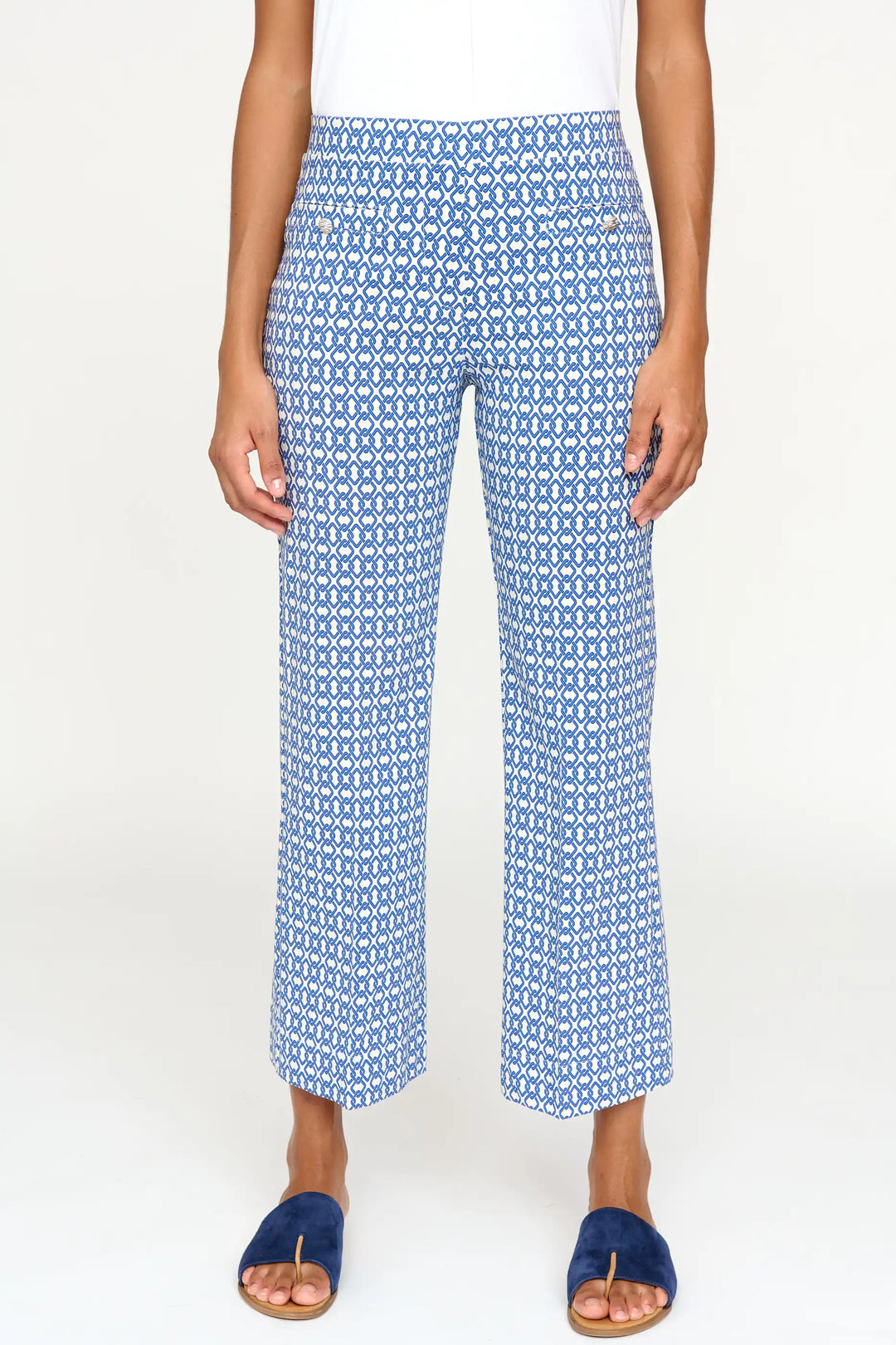 Front view of 'Dariana' style pants featuring a detailed blue and white porcelain-like pattern, mid-rise waist, and cropped straight-leg fit, paired with dark blue slide sandals.