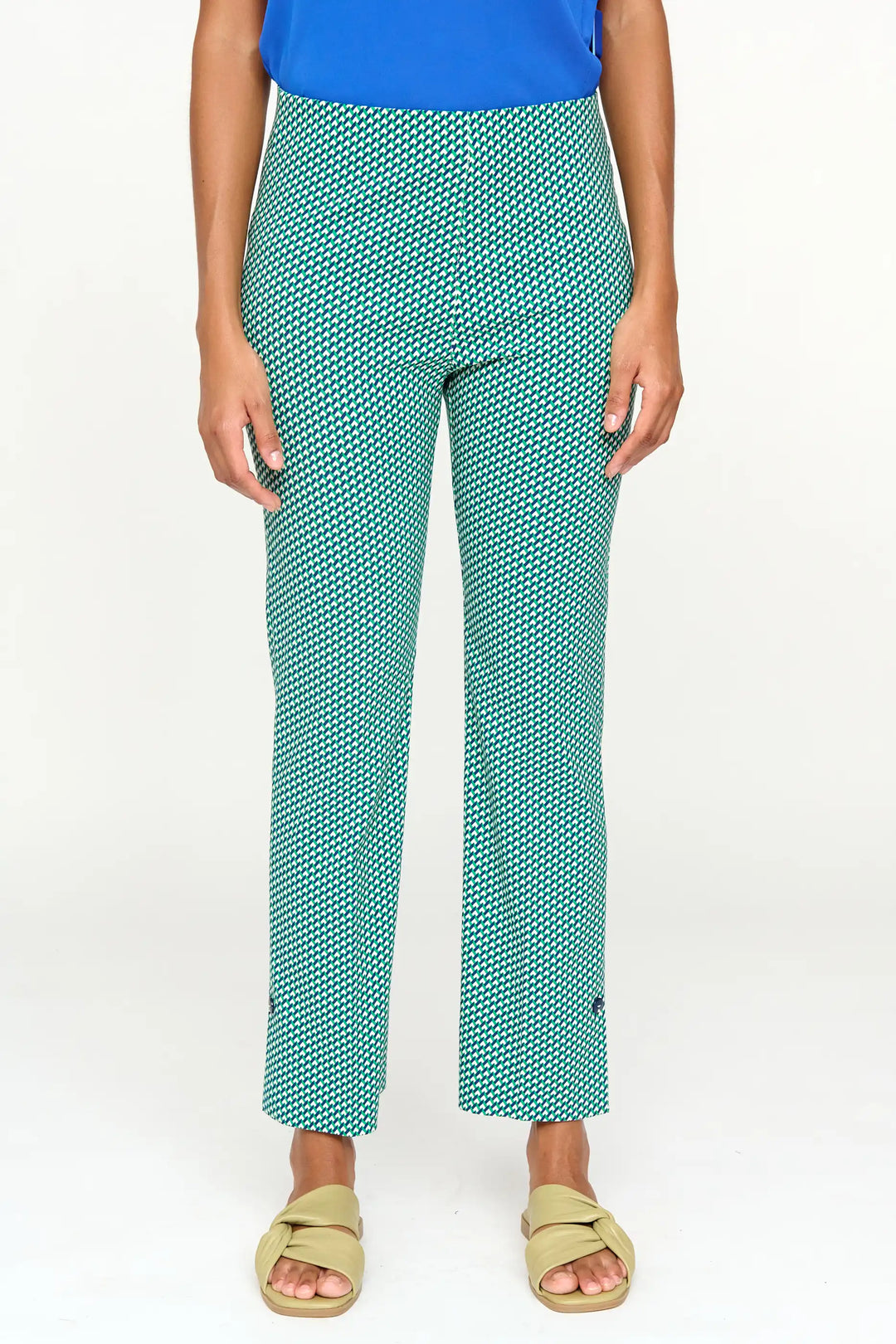 Front view of 'Donora' style trousers with a green and white geometric print, slim fit, cropped length, paired with olive green sandals.