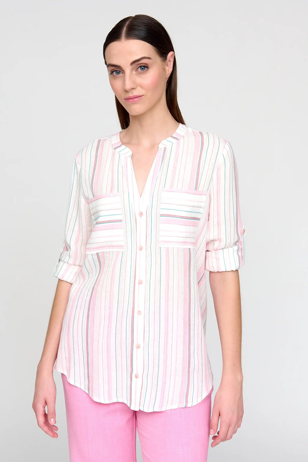 Model in 'Panela' style blouse featuring pastel vertical stripes and full-length sleeves buttoned up to a 3/4 length, complemented by light pink trousers.