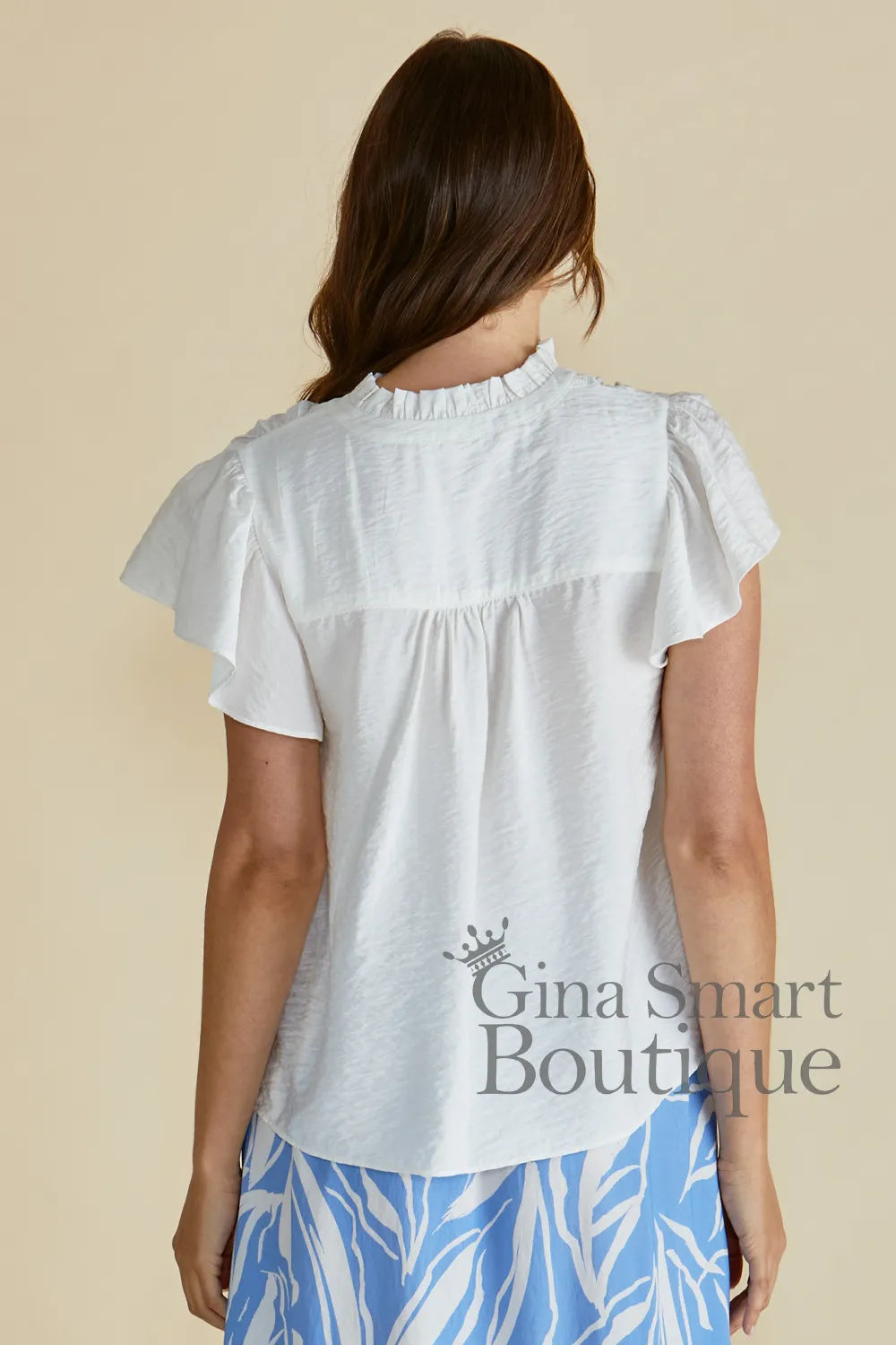 Betty Basics Lyra Blouse back view is a white flutter sleeve blouse with a tie front neckline available at Gina Smart Boutique