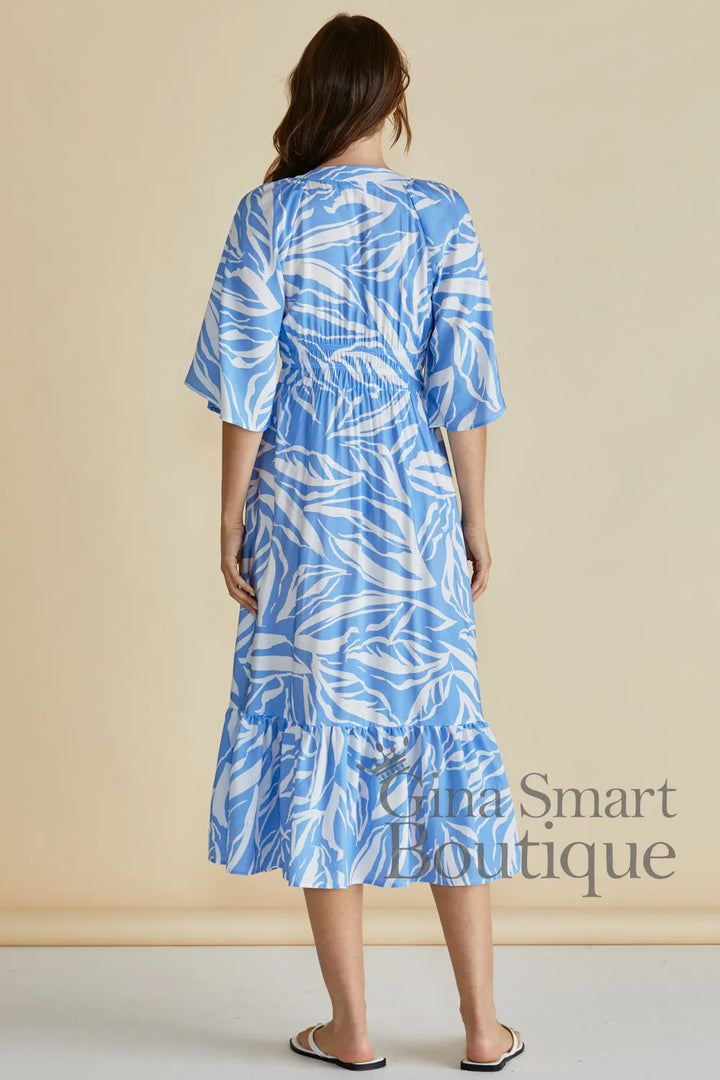 Betty Basics Moxie Dress back view is a blue and white leaf print midi dress with a smocked waist and button down front.  Available at Gina Smart 