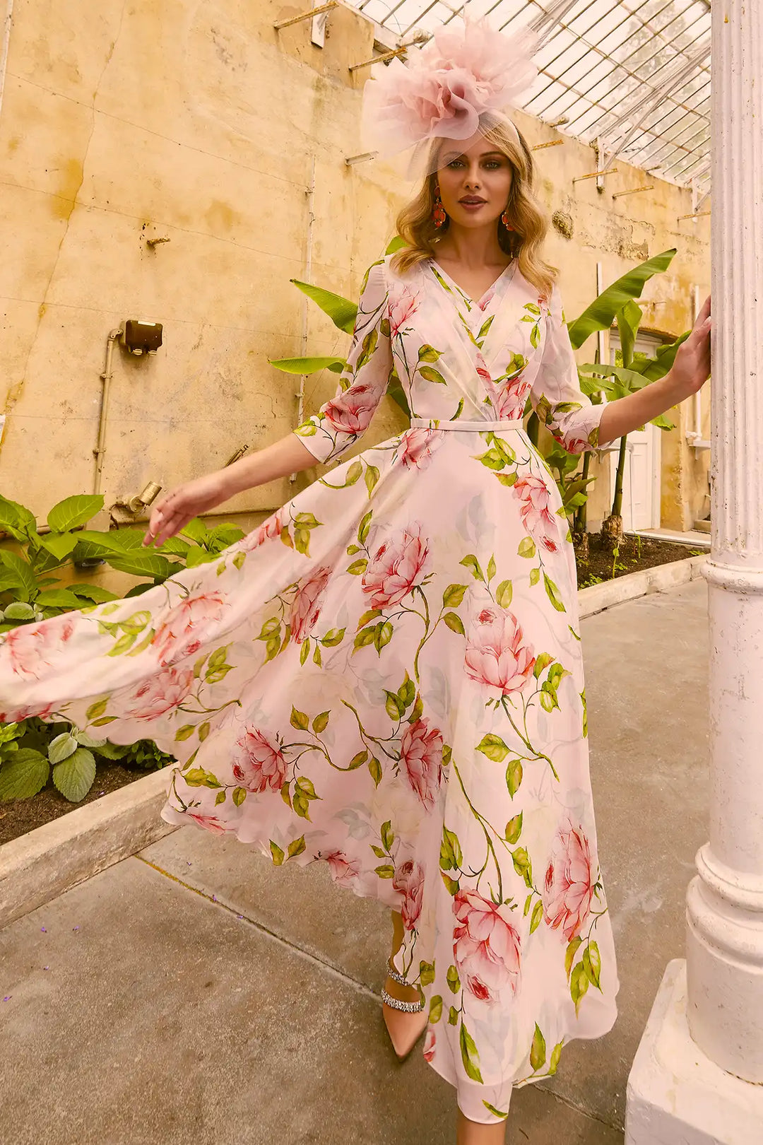 Woman in Invitations by Veni 36012 dress with rose and green floral print, flowing A-line skirt