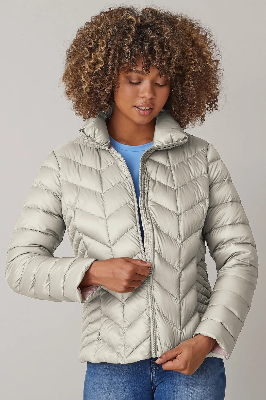 Woman wearing a champagne coloured quilted jacket with high collar and full-length zipper, over a blue shirt and jeans, style 0124-2040-62-11