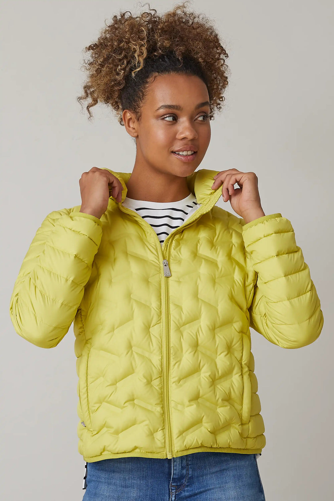 Model sporting a bright yellow quilted jacket with a front zipper, paired with a striped top underneath, looking to the side with a thoughtful expression, style  0124-2450-63-55