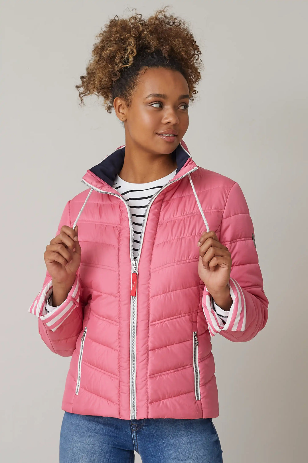 Model wearing a pink quilted jacket with zippered pockets and adjustable hood, layered over a blue shirt, paired with blue jeans, style 0124-2454-66-36