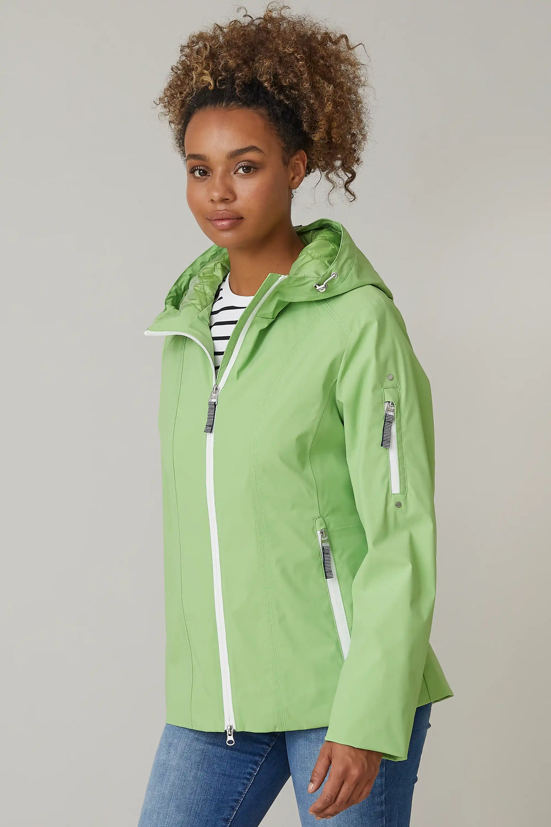 Model in a lime green jacket with hood and zippered pockets, over a striped top and blue jeans, style 0124-2494-88-49