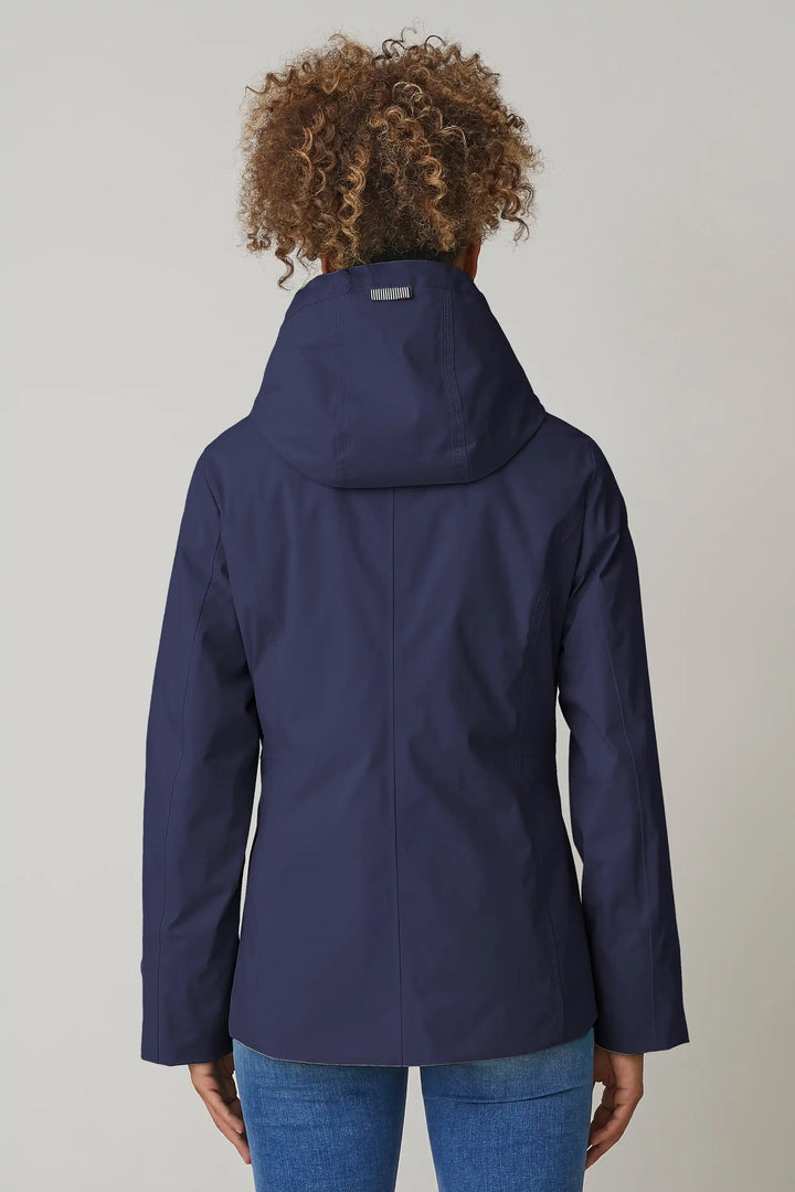 Back view of a model sporting a navy windbreaker with a hood and zippered pockets, layered over a striped shirt for a casual, functional spring outfit, style 0124-2494-88-50