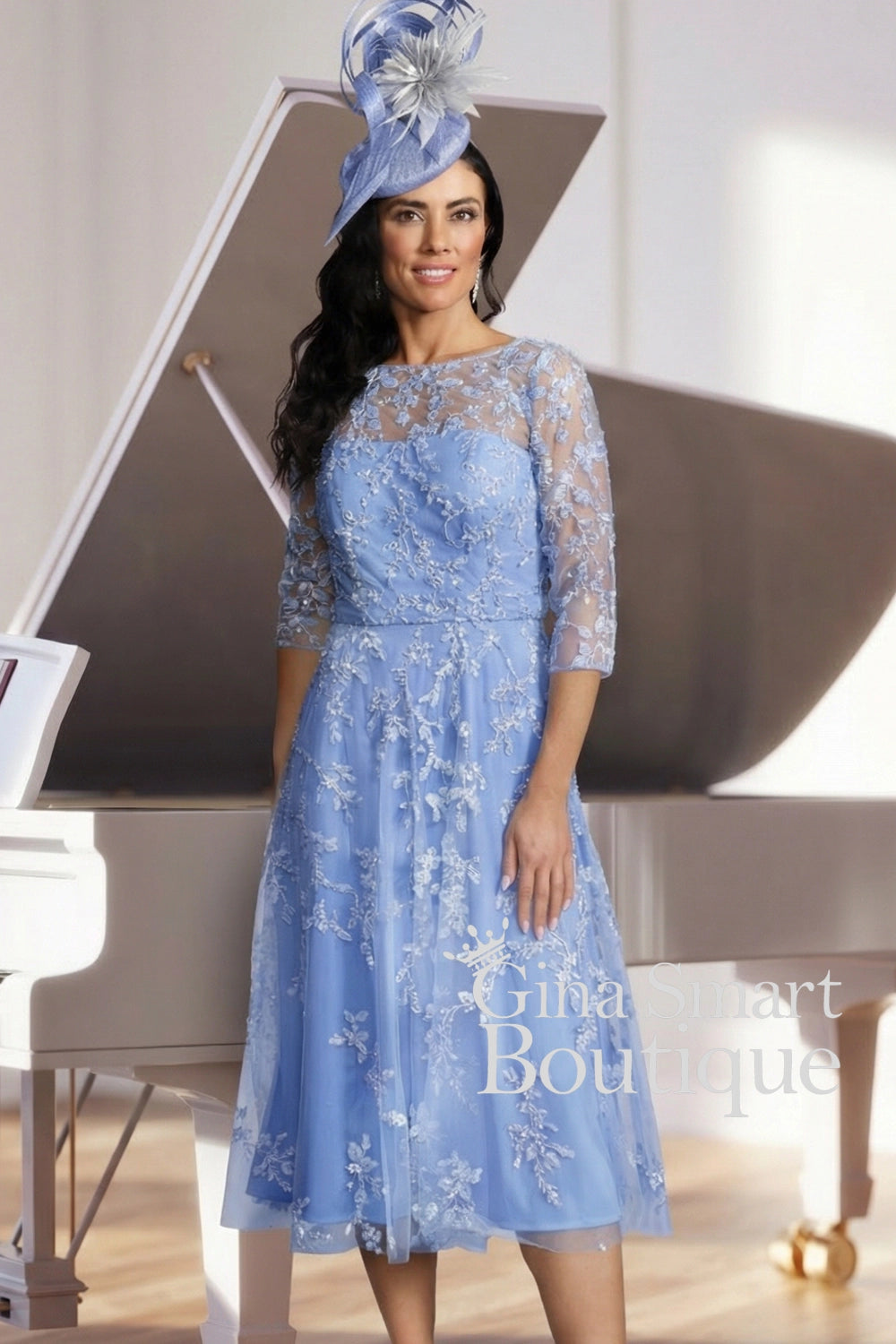 Woman in a blue lace dress standing in front of a piano.